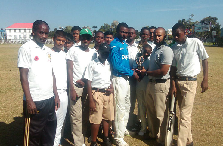 Charlestown Secondary captain Qumar Torrington receives the trophy from GCB representative Anthony D'Andrade.