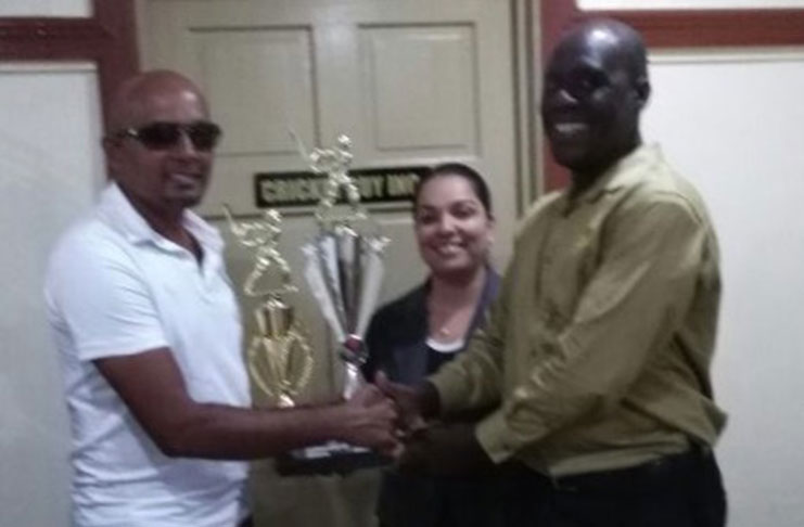 Former West Indies pacer Colin Stuart right, hands over trophies to Rafeek Kassim in the presence of Melisa Bishundial