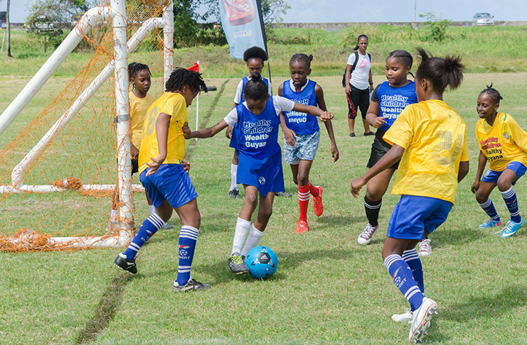 A player uses her skill to evade defenders in yesterday’s opening round of the Smalta Girls Schools football Tournament (Delano Williams Photo)