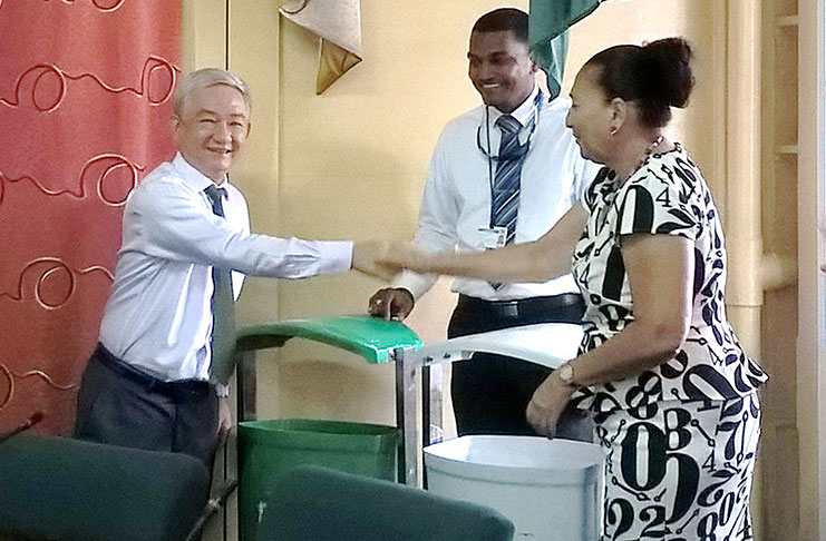 Chinese Ambassador, Zhang Limin (at left) hands over the garbage receptacles to Mayor Patricia Chase-Green and Solid Waste Director, Walter Narine