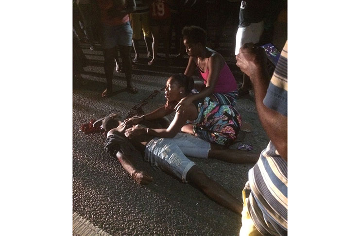 The lifeless body of 25-year-old Frank Deflorimonte Jr being sheltered by his weeping sister on Sunday evening on the Rupert Craig Highway