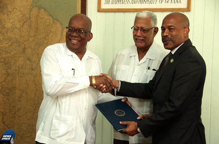 Finance Minister Winston Jordan (left) and CDF Chief Executive Officer (CEO) Rodinald Soomer (right) exchange signed agreements on Wednesday in the presence of Agriculture Minister Noel Holder (centre)