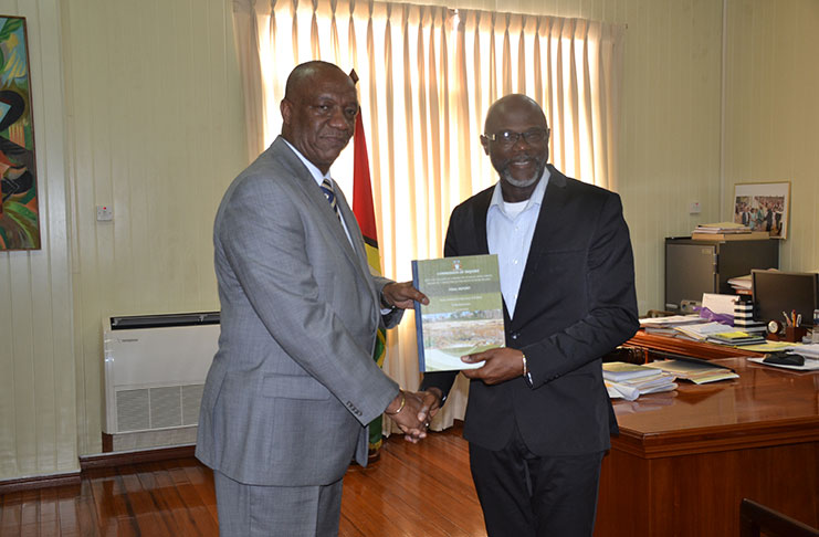 Minister of State Joseph Harmon receiving the final report into Puruni mining pit collapse from Rear Admiral (ret’d) Gary Best at his office at Ministry of the Presidency