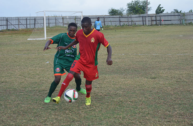Eusie Phillips being pursued by right back Rishaun Ritch of Conquerors.