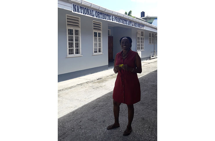 Rehabilitation Officer Cynthia Massay stands in front of the National Orthotic & Prosthetic Appliance Workshop during the tour of the Ptolemy Reid Rehabilitation Center.