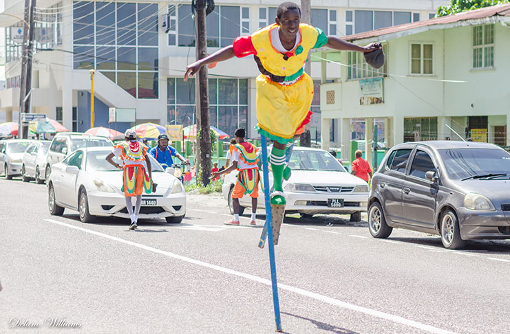 A masquerader dancing on one foot
while the others solicit money from
drivers on Camp Street, Georgetown.
[Delano Williams photo]