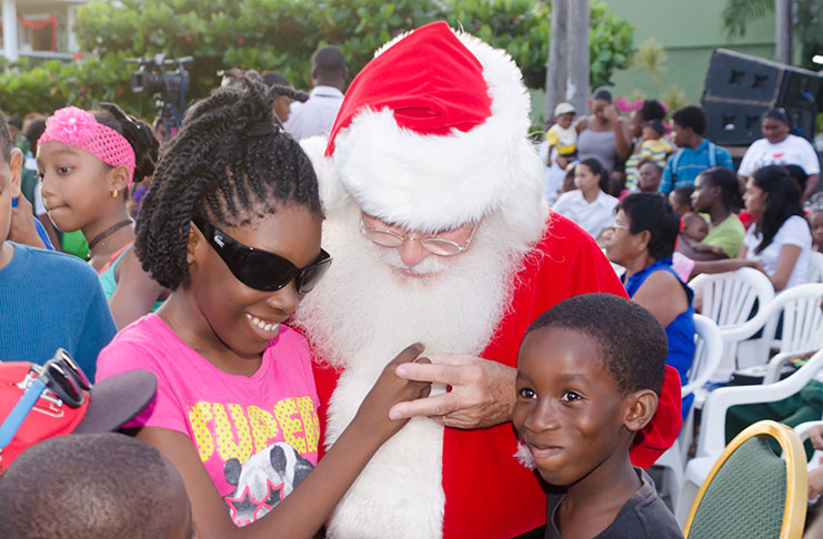 Santa
Claus spreads joy to 12-year-old
Mekyla Belgrave, who is blind,
and her brother Micqual, 8, at
Rahaman’s Park. [Delano Williams
photo]
