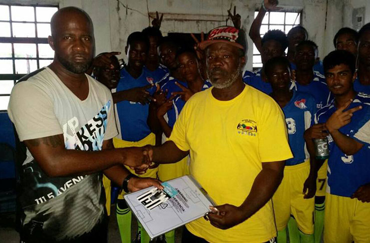 Former National goalkeeper and present National Goalkeeper Coach, Andre Hazel (L) makes a presentation of a Tactical Board and a Fox 40 whistle to Black Pearl FC and long standing football Coach, Peter 'Michelin' Gulliver minutes before last Monday's U-19 league game against Conquerors. Hazel said it is his way of recognizing the tremendous works of the 1998 GFF's Coach of the year who started at Pele FC over three decades ago.