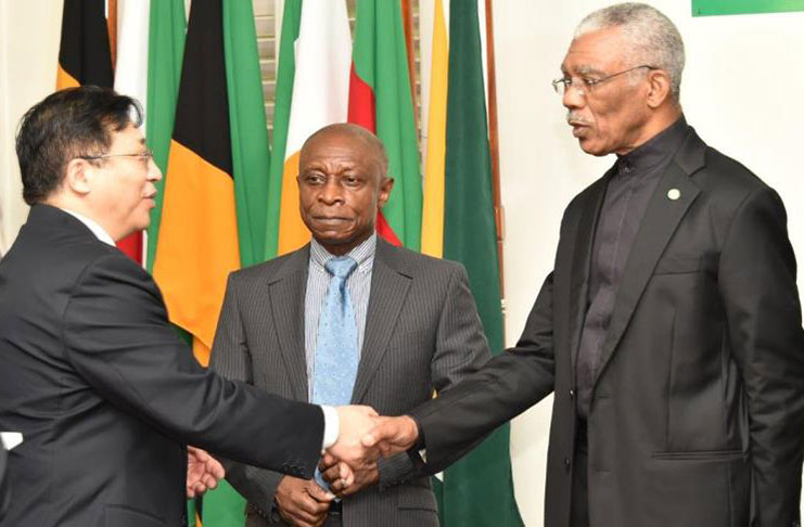 President David Granger and newly accredited Ambassador to Guyana, Mr. Cui Jianchun exchange a handshake as acting Prime Minister and Minister of Foreign Affairs, Mr. Carl Greenidge looks on