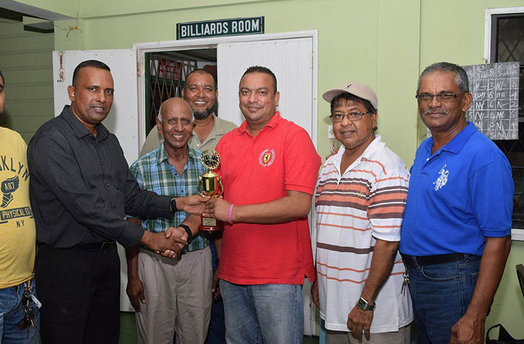 Everest Cricket Club president Rajesh Singh (right) hands over the winning trophy to Boodnarine Persaud, who collected on behalf of the victorious team. Skipper Manniram Shew is second from right.