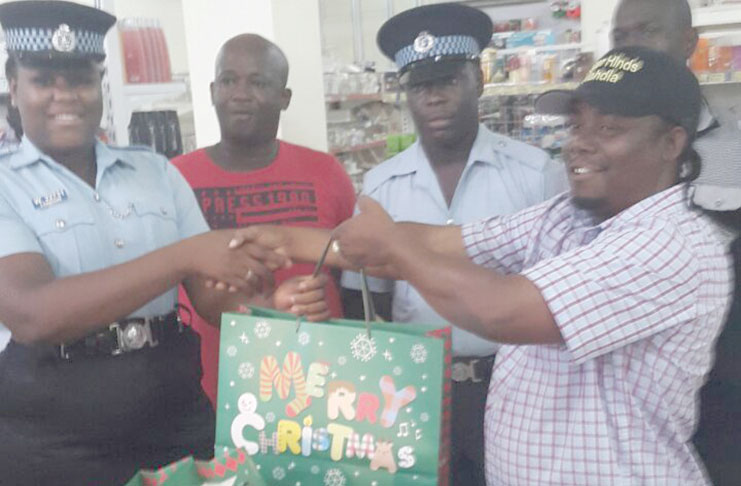 Woman Constable La-Seena London receiving some of the gifts for police ranks from businessman Roger Hinds, while Constable Mark Grimmond at right and Inspector Marvin Small, left, look on