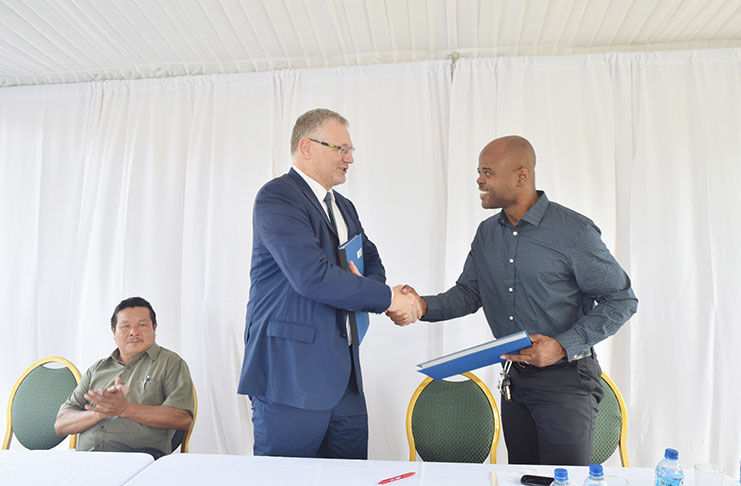 European Union Ambassador, Jernej Videtic (left), exchanges a handshake with Executive Director of Youth Challenge Guyana, Dimitri Nicholson, following  inking of the funding agreements