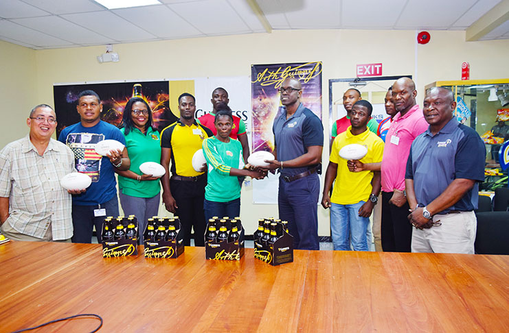 Guinness Brand Manager Lee Baptiste hands over a ball to a female player to signal the launch of the Inaugural Guinness VII’s tournament while Banks DIH staff, GRFU executives and players look on.