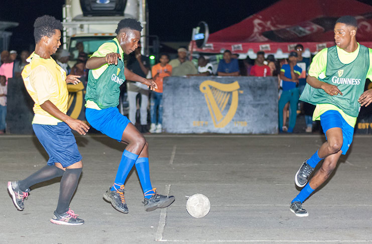 An ESPN player (right) attacks the Young Ballers duo during Saturday evening’s Colors/Guinness street football championships at Pouderoyen. (Delano Williams Photo)