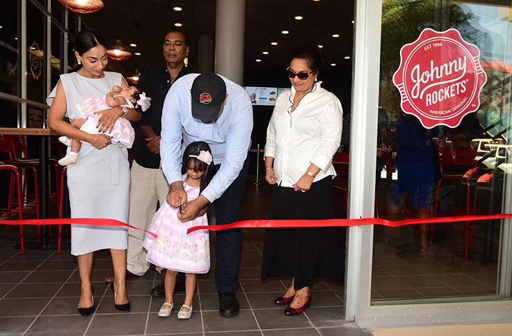 Co-owner Ameir Ahmad with his daughter in the ribbon-cutting ceremony to declare the business open on Thursday while his wife, Preeta Mangar, her other daughter and relatives look on.