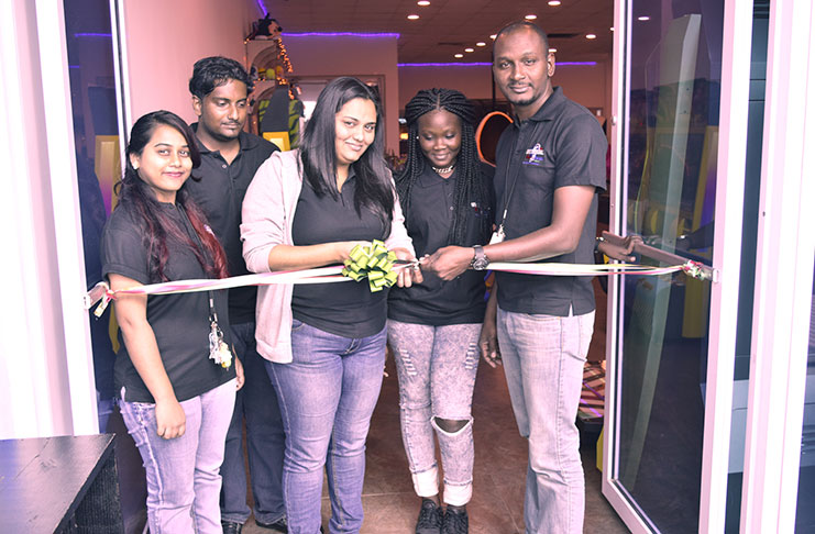Operations Assistant, Adrian Munroe, (right) and Universal Games Manager, Bonita Lhakram (centre) and other staff of the arcade during the ribbon-cutting of the new PS4 area on Thursday (Photos by Cullen Bess-Nelson)