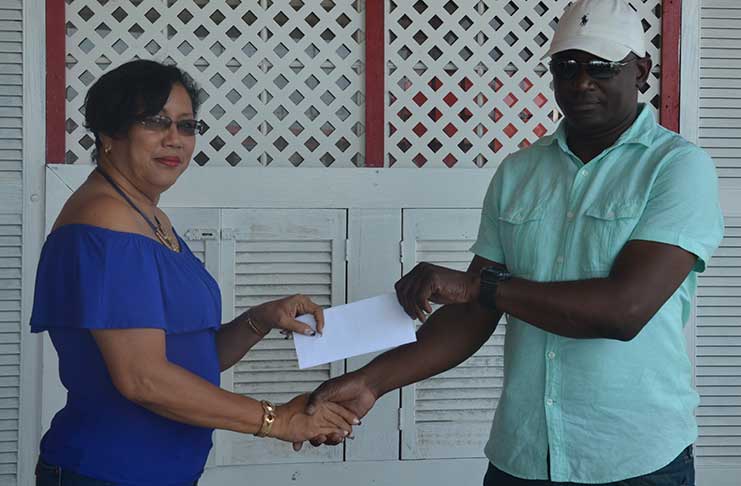 GMR&SC official Desrie Lee collects the cheque from Mohamed's Enterprise representative Udoh Kanu.