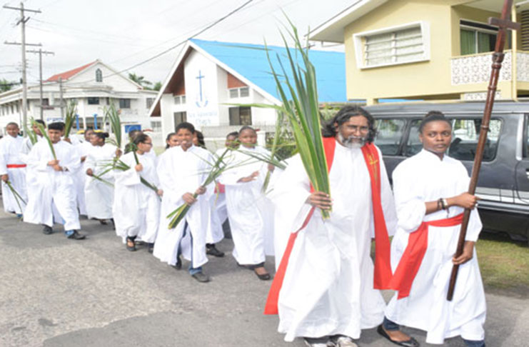 Rev. Godfrey Veerasammy. S.J. in the lead as the procession makes its way out of Our Lady of Fatima R.C. Church, North Road Bourda, before entering the Bourda Cricket Stadium for a joint  Palm Sunday Mass in 2015.