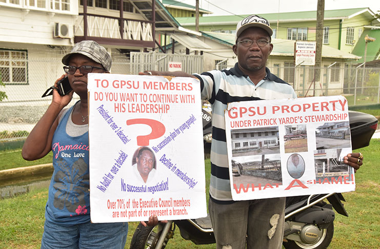 Two supporters of Gregory Gaspar’s Team Change stand opposite the GPSU headquarters on Sunday bearing placards (Photos by Adrian Narine)