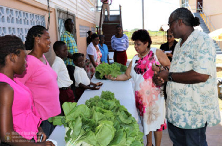 Minister of Social Protection, Amna Ally examines produce on display by some of the single-parent farmers
