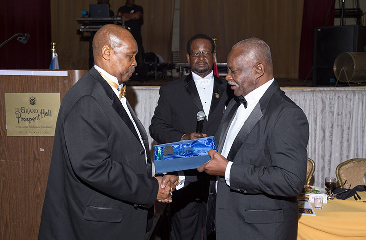 Minister of Citizenship Winston Felix, presents an award to past president Leon Gibbons.