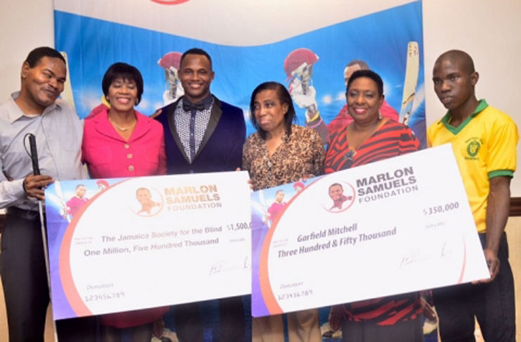 Jamaica and West Indies cricketer is third from left while members of the Jamaica Society for the Blind display the cheques.