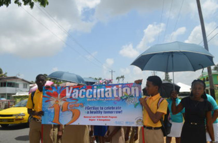 Students of the Brickdam Secondary School holding the 15th Vaccination Week in the Americas poster