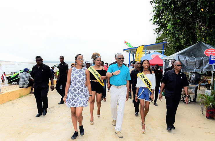 President David Granger takes a walk on the beach with his grand-daughter Athena Gaskin and two of the contestants in the Miss Bartica Regatta pageant