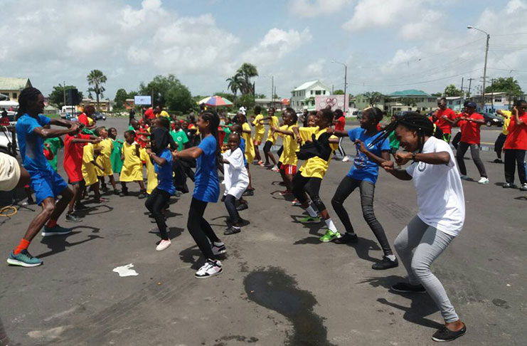 Fitness Instructor Tyson English takes the smiling students and teachers through a few routines at Square of the Revolution yesterday. (Tamica Garnett photo)