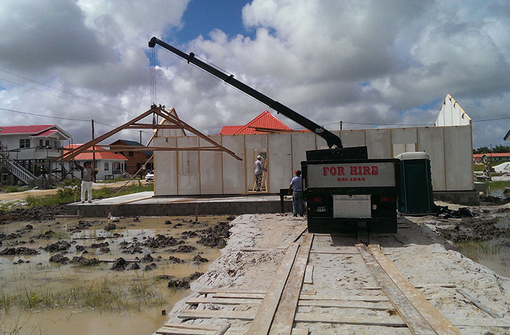 A crane being used to put the pieces of the house together