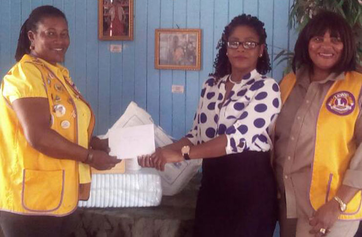 June Leitch handing over a donation of adult pampers to a representative of the Palms Institution. Looking on is Lions Club member, Roxanne Luckie
