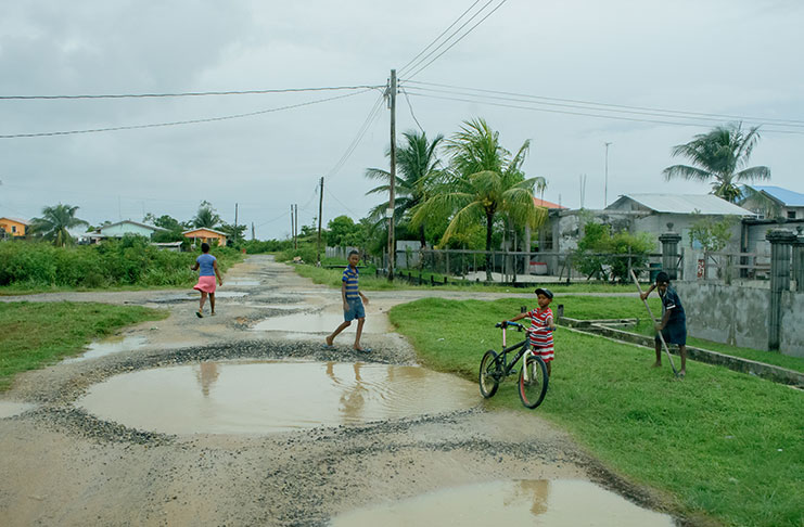 This little boy at right is using a shovel to dig a narrow track to drain water from the road into a nearby gutter (Photos by Samuel Maughn)