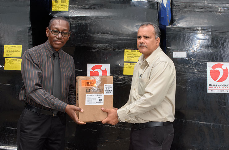 CEO Allan Johnson (left) receives a token from CEO Kent Vincent of Food for the Poor (right).