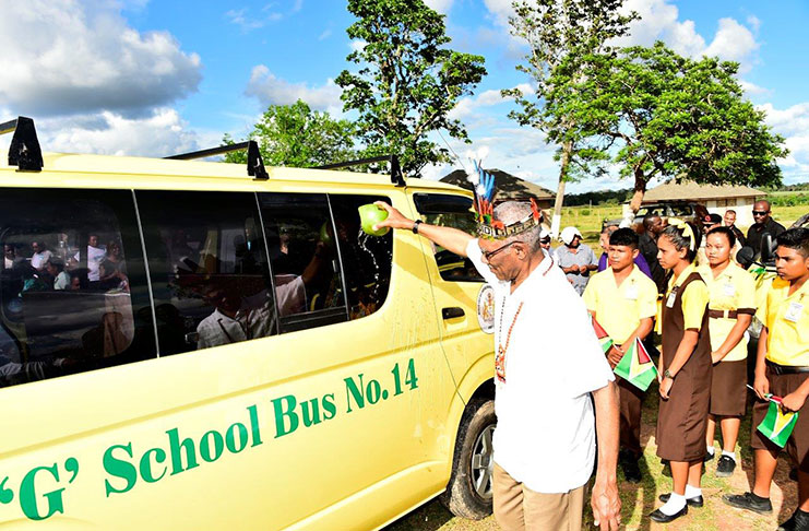 These students look on as President David Granger symbolically commissions one of two school buses, which were donated to the community to transport children to school at Annai.