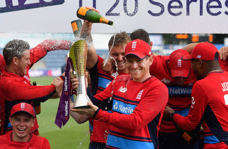 Eoin Morgan lifts the series trophy as the champagne corks pop in the background in Cardiff.