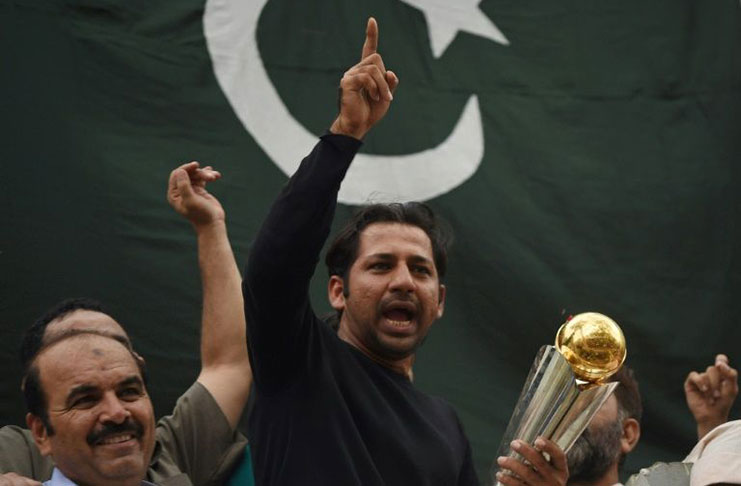 Pakistani cricket captain Sarfraz Ahmed acknowledges fans as he holds the Champions Trophy following his arrival from London in Karachi.
