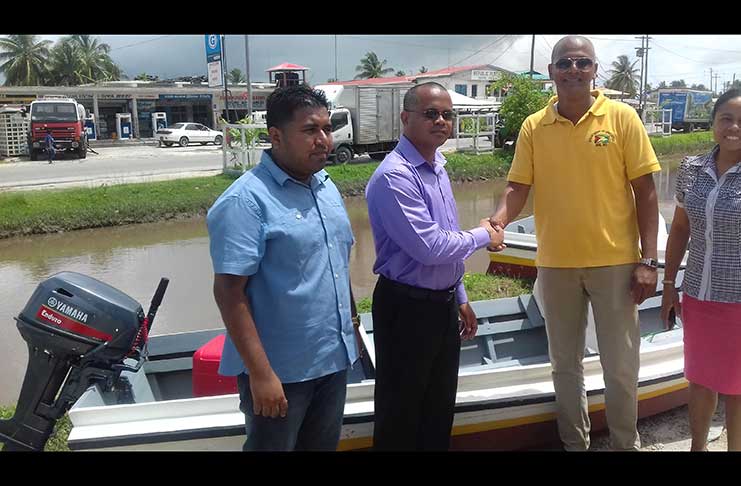 REO of Region Two, Derrick Persaud, handing of one of five boats and engines to District Education Officer, Deodath Singh, in the presence of the Regional Engineer, Latchman Singh