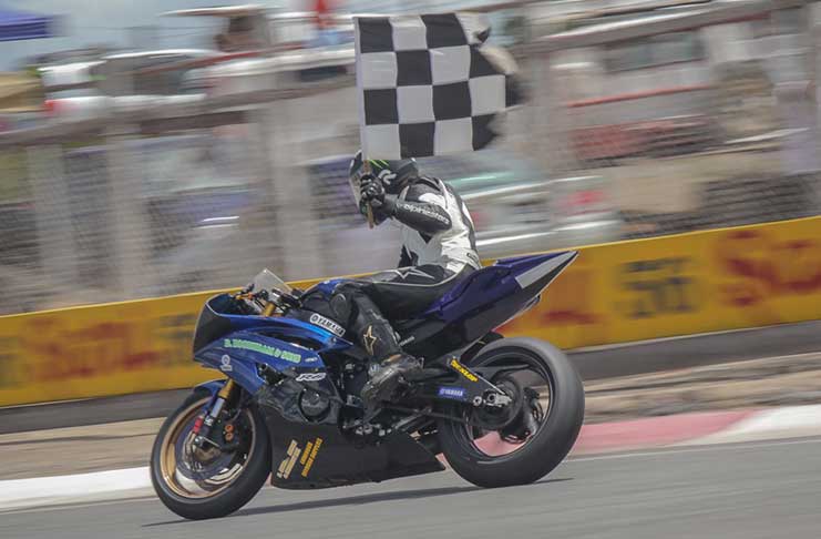 Heemand Boodhram displays his chequered flag after winning the lone superbike race of the day.