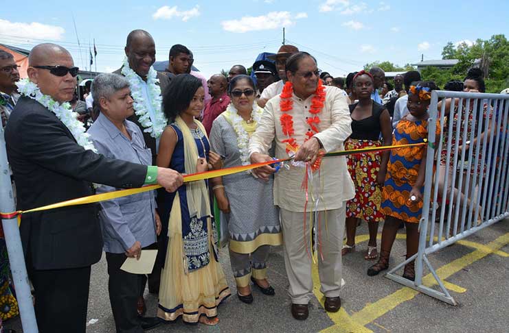 Minister of Social Cohesion, Dr George Norton, first left, assists Acting President and
Prime Minister Moses Nagamootoo to cut the ceremonial ribbon to officially declare
open Harmony Village-New Amsterdam Cultural Fest. Minister of State, Mr. Joseph
Harmon (third from left, background), and Minister within the Ministry of Finance, Mr.
Jaipaul Sharma (second from left) and Mrs. Sita Nagamootoo are also pictured