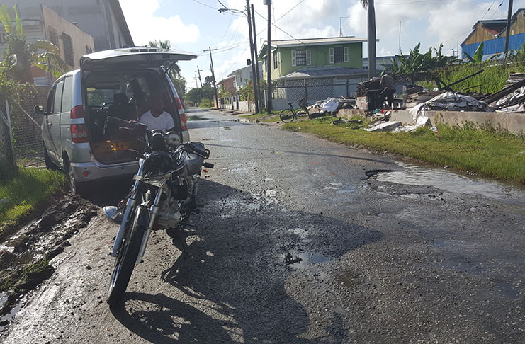 The damaged vehicle and motorcycle parked on Lama Avenue, Bel Air Park after the accident. In photo is the pothole the biker tried to avoid.