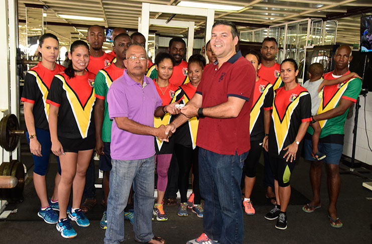 GHB president Phillip Fernandes (right) collects a membership card from the Buddy’s Gym representative during Friday’s ceremony. In the background are several members of team Guyana. (Adrian Narine Photo)