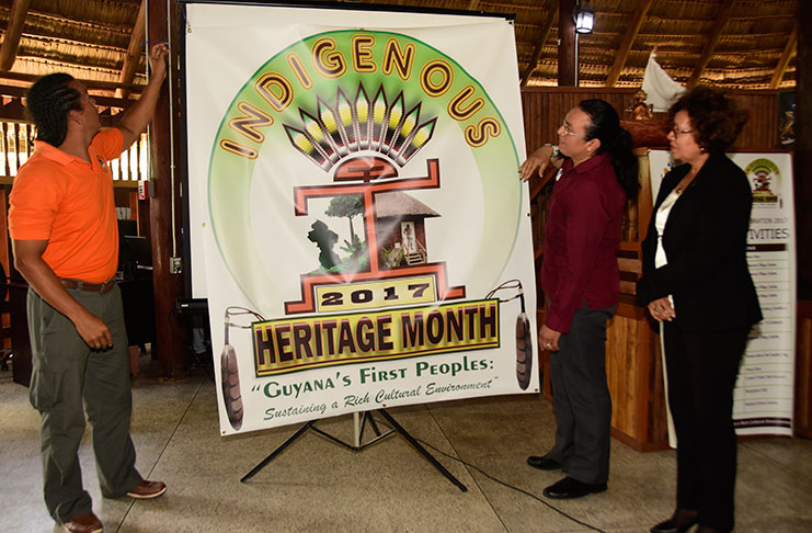 National Toshaos Council Vice-Chairman, Lenox Shuman, (left) assists in unveiling the “Heritage Logo” at Wednesday’s event. Minister within the Ministry of Indigenous Peoples Affairs, Valerie Garrido-Lowe, is at right while staffer Anil Roberts is second from left (Adrian Narine photo).