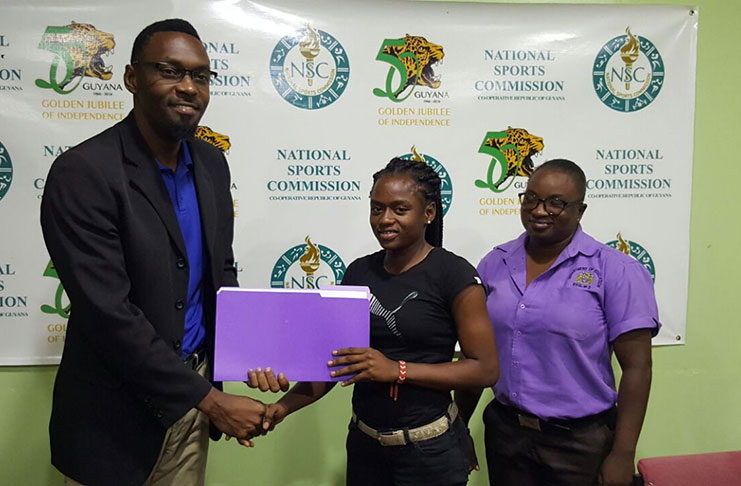 Director of Sport Christopher Jones (left) hands over a signed MOU with sprinter Onessha Rogers in the presence of her mother yesterday.