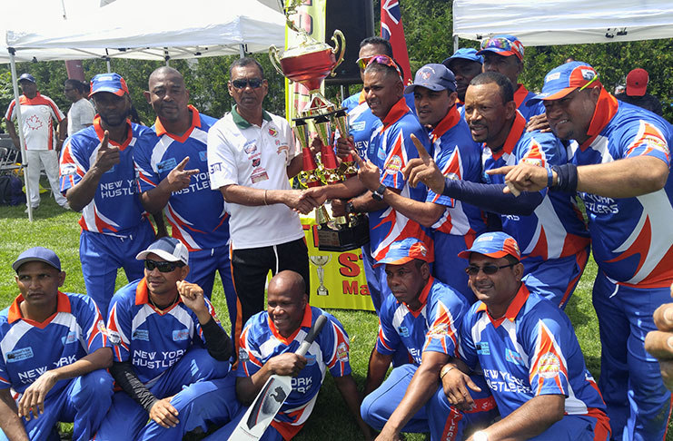 Ramesh Sunich, of Trophy Stall, hands over the Masters trophy to captain Shameer Sadloo while other members of the victorious New York Hustlers celebrate.