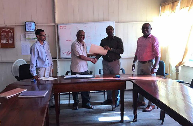 GFF president Wayne Forde (second from right) receives signed MoU from Eccles-Ramsburg NDC chairman Mahamad Hafeez.