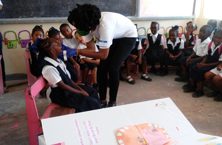 A student getting her teeth varnished with fluoride by founder of The Healthy Smiles Project, Jonnel Mortley