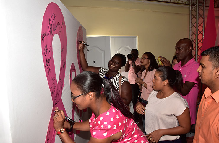 These young ladies register their names to the fight against breast cancer at the launch of ‘Pinktober’- a month-long activity
calling for more action on breast cancer awareness on Thursday (Adrian Narine photo)