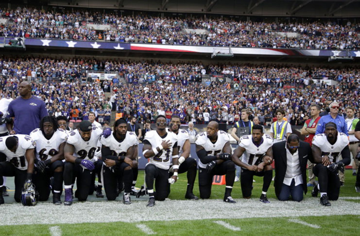 Baltimore Ravens players, including former player Ray Lewis, second from right, kneel down during the U.S. national anthem before an NFL football game.
