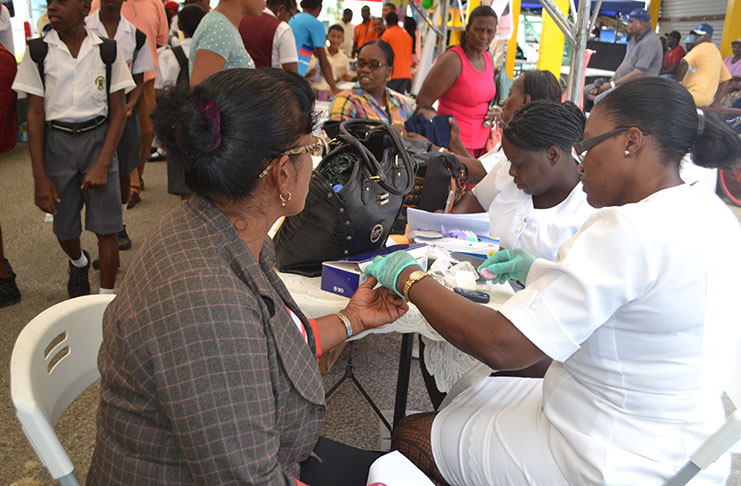 Health workers assist a patron at the career fair with her medical checkup
