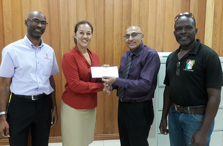 GOA president K. Juman Yassin hands over a cheque to the secretary of the GHB Tricia Feidtkou while executive members look on.